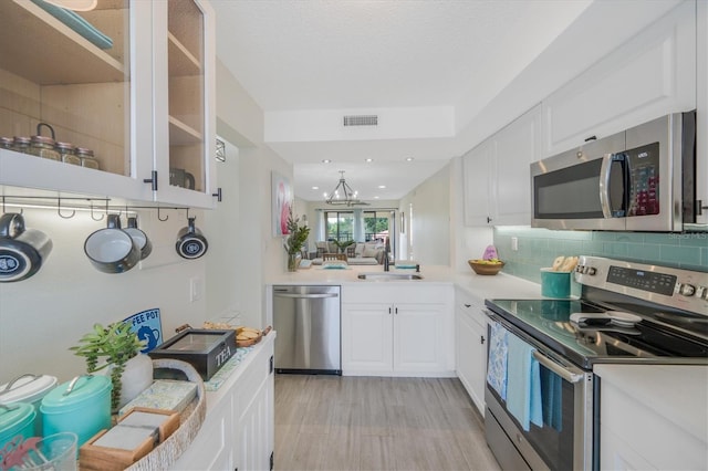 kitchen featuring an inviting chandelier, white cabinets, sink, tasteful backsplash, and stainless steel appliances