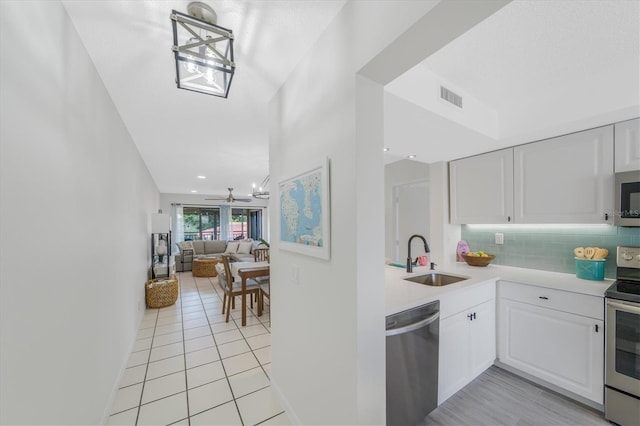 kitchen with backsplash, sink, light tile patterned flooring, white cabinetry, and stainless steel appliances