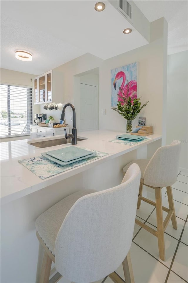 kitchen with a kitchen breakfast bar, kitchen peninsula, sink, and light tile patterned floors