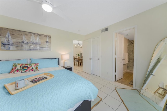 tiled bedroom with ceiling fan with notable chandelier, ensuite bath, and a closet