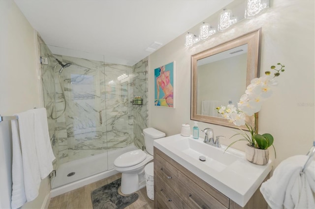 bathroom with hardwood / wood-style floors, vanity, an enclosed shower, and toilet