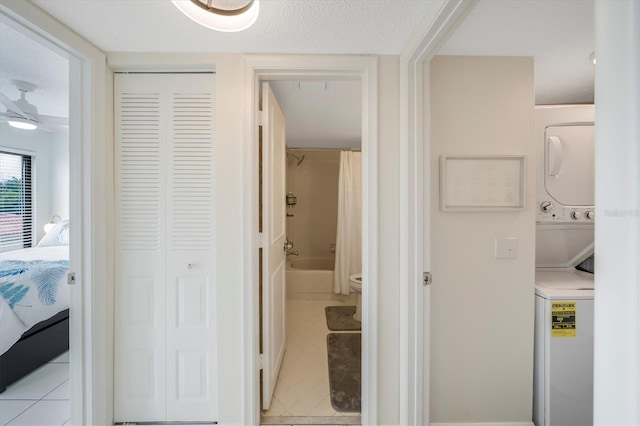 hallway with light tile patterned floors and stacked washer and clothes dryer