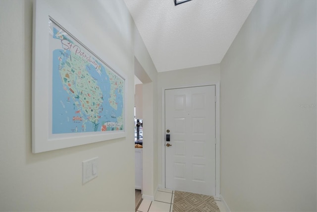 doorway to outside featuring light tile patterned floors and a textured ceiling