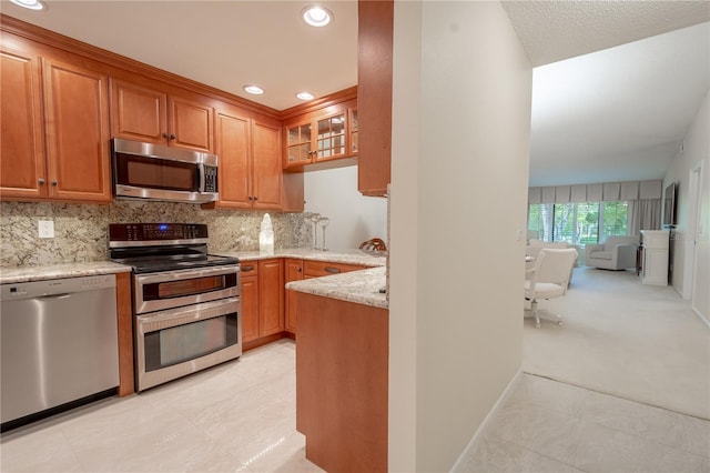 kitchen featuring light stone countertops, appliances with stainless steel finishes, light colored carpet, and backsplash