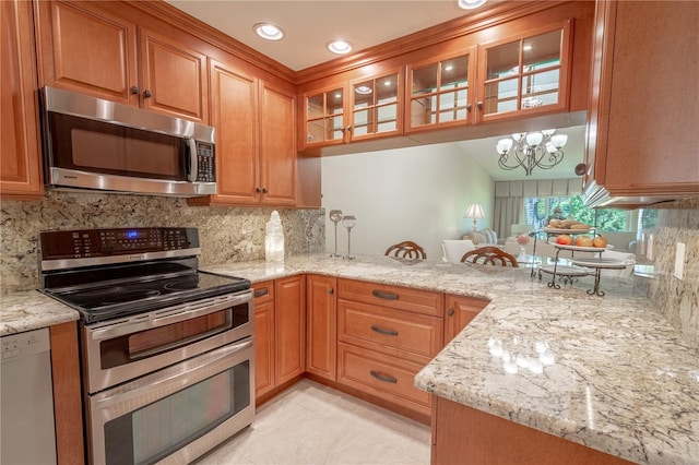 kitchen featuring stainless steel appliances, light stone countertops, an inviting chandelier, and kitchen peninsula