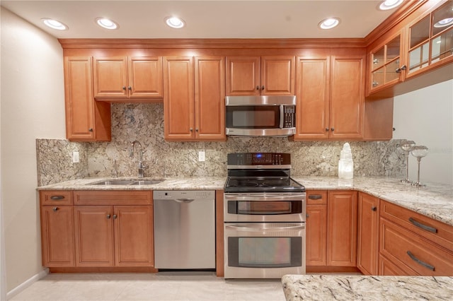 kitchen with light stone counters, sink, tasteful backsplash, and appliances with stainless steel finishes