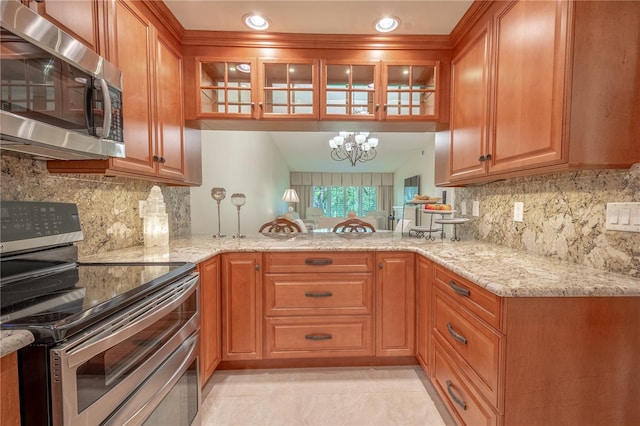 kitchen with stainless steel appliances, tasteful backsplash, light stone countertops, and a chandelier