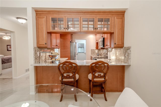 bar featuring tasteful backsplash, ceiling fan, stainless steel appliances, and light stone counters