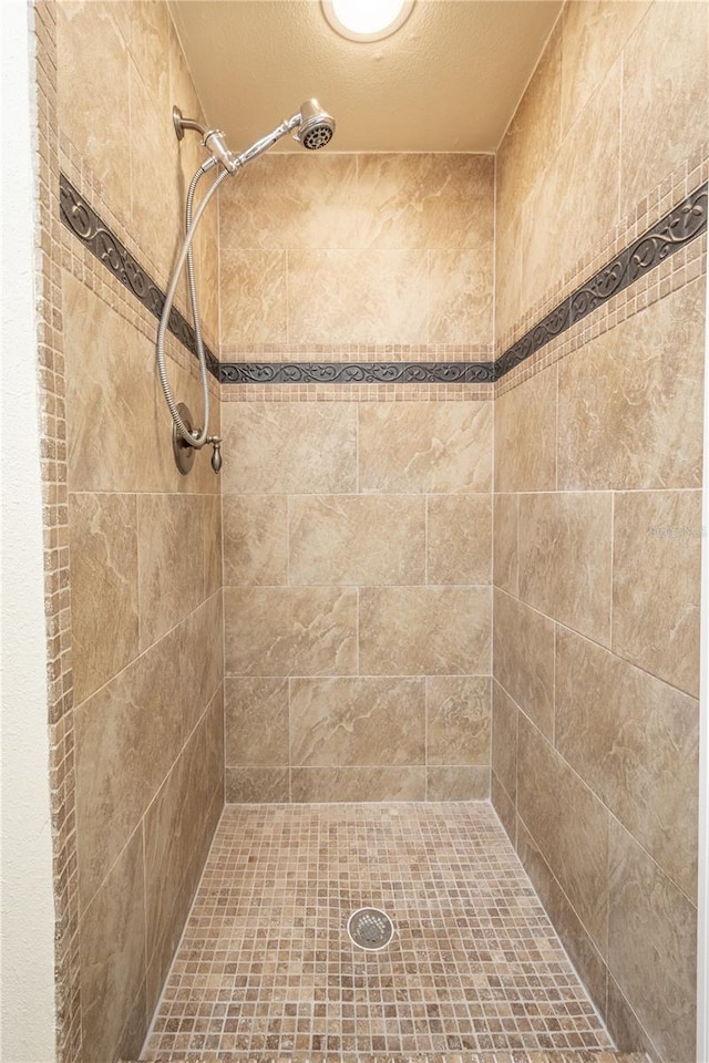 bathroom with a textured ceiling and a tile shower