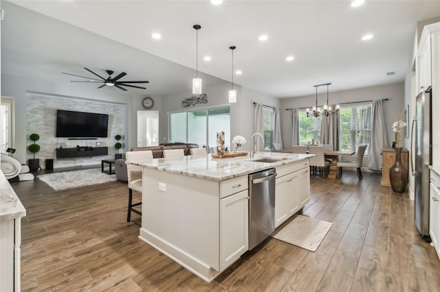 kitchen featuring appliances with stainless steel finishes, white cabinetry, a center island with sink, and a sink