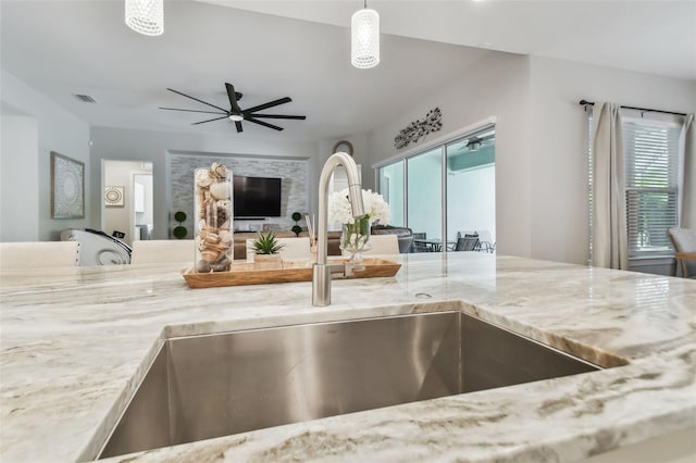 kitchen with visible vents, a ceiling fan, open floor plan, hanging light fixtures, and a sink