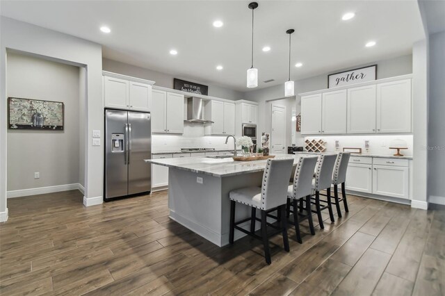 kitchen with tasteful backsplash, white cabinets, hanging light fixtures, a kitchen island with sink, and stainless steel appliances