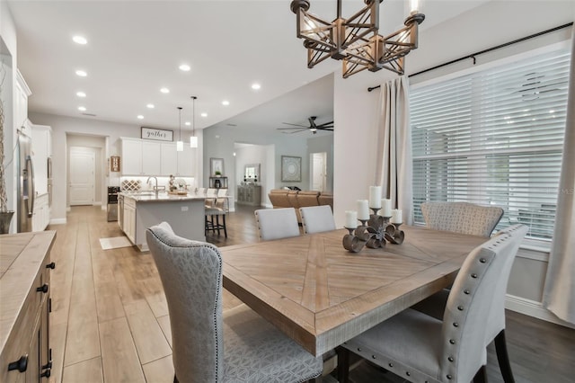 dining area with ceiling fan with notable chandelier, light wood-type flooring, baseboards, and recessed lighting