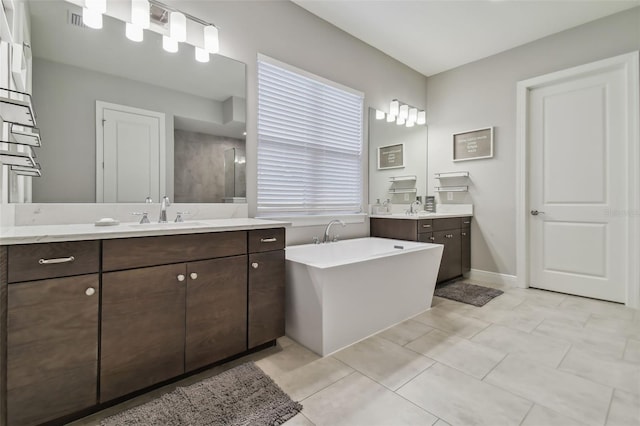 full bath with a sink, a soaking tub, two vanities, and tile patterned floors