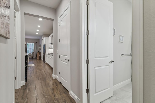 hallway with light wood-type flooring, baseboards, and recessed lighting