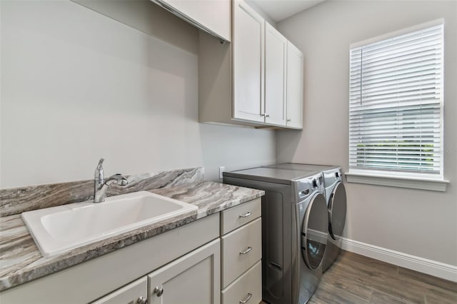 washroom with dark wood-style floors, washer and clothes dryer, cabinet space, a sink, and baseboards