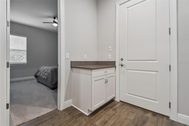 interior space featuring ceiling fan, dark wood-style flooring, and baseboards