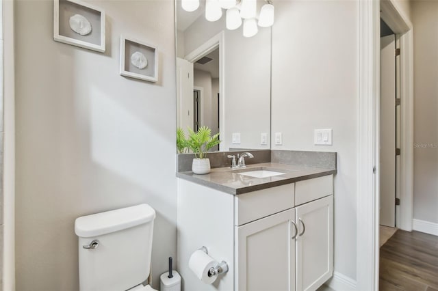 bathroom featuring toilet, baseboards, wood finished floors, and vanity