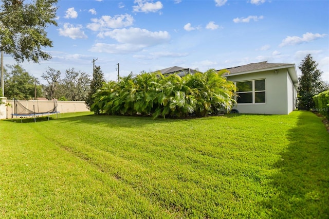 view of yard with a trampoline and fence