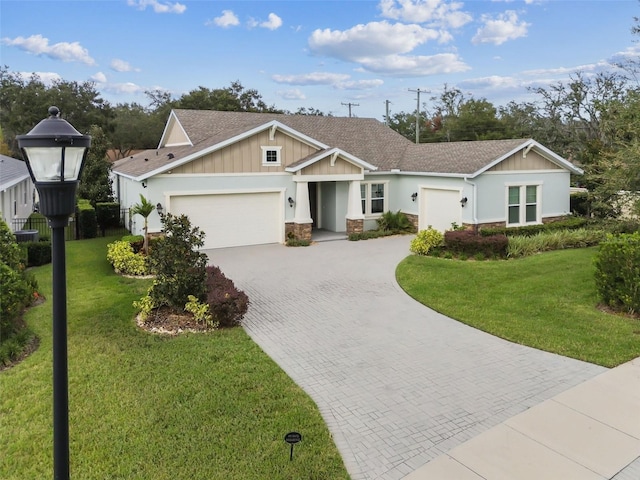 view of front of house with stone siding, decorative driveway, an attached garage, and a front yard