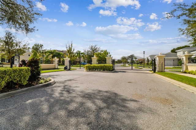 view of street with a residential view, a gate, curbs, and a gated entry