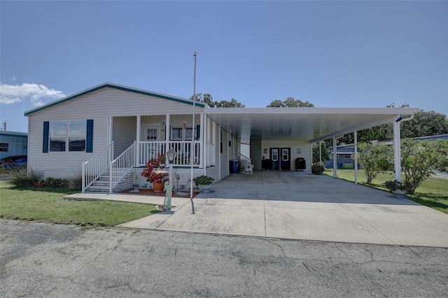 manufactured / mobile home with a front yard, a porch, and a carport