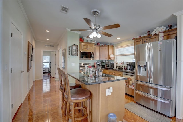 kitchen featuring a breakfast bar area, stainless steel appliances, dark stone countertops, crown molding, and a center island