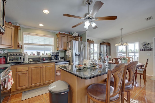 kitchen featuring a kitchen island, dark stone countertops, sink, ceiling fan with notable chandelier, and stainless steel appliances