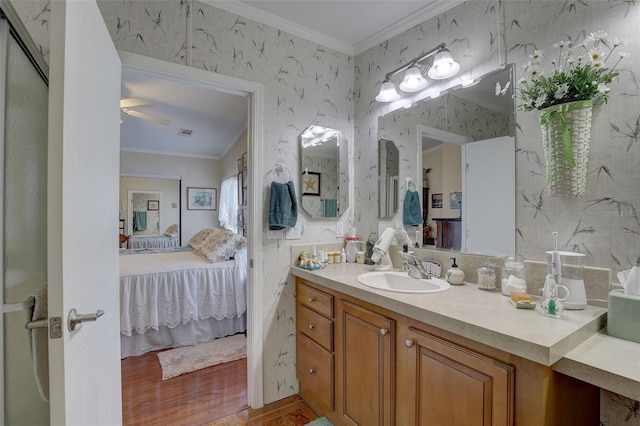 bathroom with vanity, hardwood / wood-style floors, ornamental molding, and ceiling fan