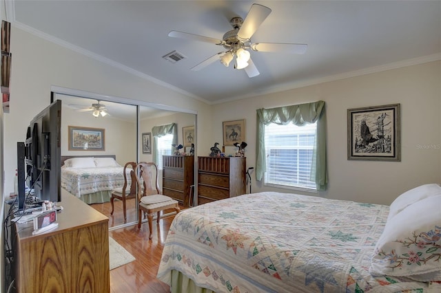 bedroom with a closet, crown molding, light hardwood / wood-style floors, and ceiling fan