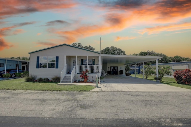 manufactured / mobile home with covered porch, a lawn, and a carport