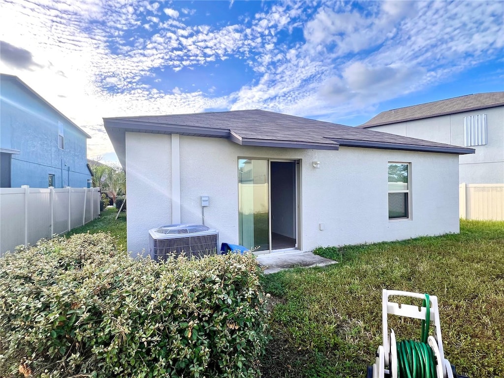 back of property featuring a yard and cooling unit