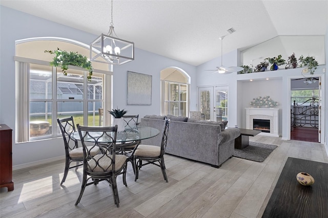 dining room with light hardwood / wood-style flooring, a wealth of natural light, and ceiling fan with notable chandelier