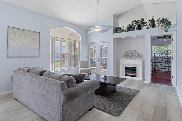 living room with french doors, high vaulted ceiling, light wood-type flooring, and ceiling fan