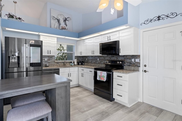 kitchen with black appliances, hanging light fixtures, white cabinetry, high vaulted ceiling, and light hardwood / wood-style flooring