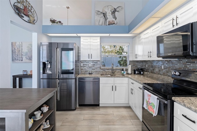 kitchen with sink, appliances with stainless steel finishes, decorative backsplash, and white cabinetry