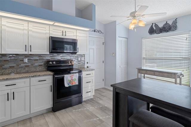 kitchen with white cabinetry, stainless steel appliances, a textured ceiling, and light wood-type flooring