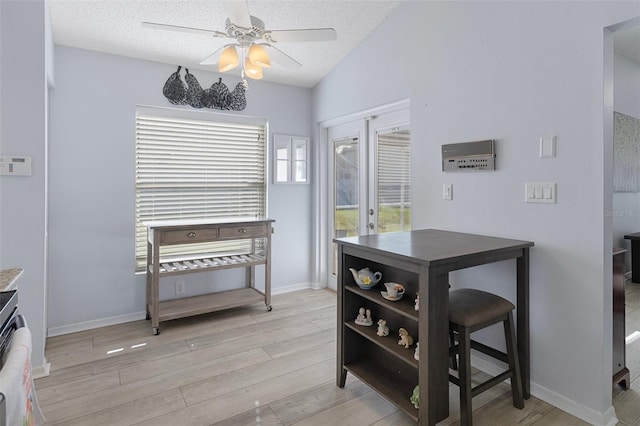 dining room featuring lofted ceiling, ceiling fan, a textured ceiling, light hardwood / wood-style floors, and french doors