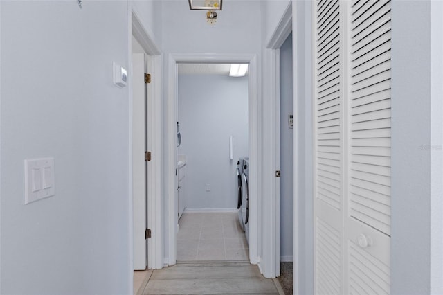 hallway with washing machine and dryer and light tile patterned floors