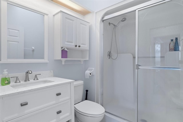 bathroom featuring a shower with door, toilet, and vanity