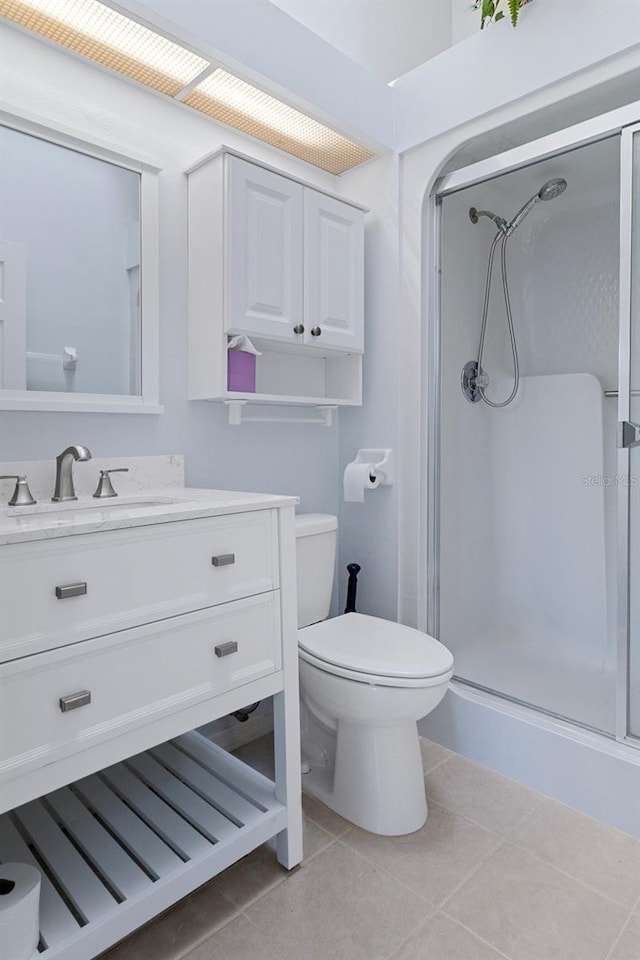 bathroom with a shower with door, toilet, tile patterned flooring, and vanity