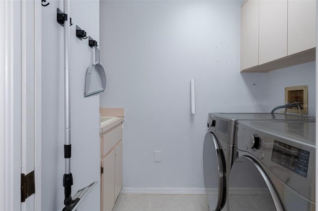 laundry area with washing machine and clothes dryer, light tile patterned floors, and cabinets