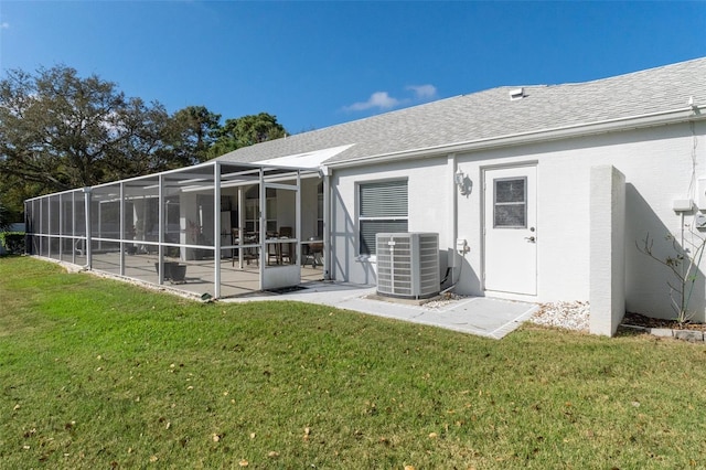 rear view of house featuring a patio, central AC unit, a lawn, and glass enclosure