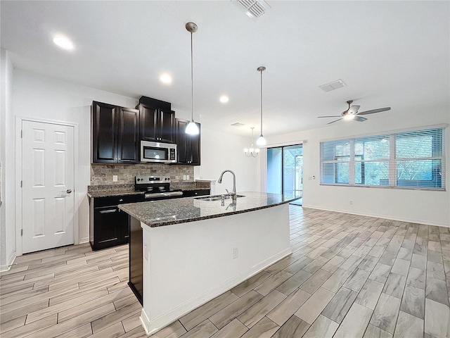 kitchen with a kitchen island with sink, stainless steel appliances, pendant lighting, light hardwood / wood-style floors, and sink