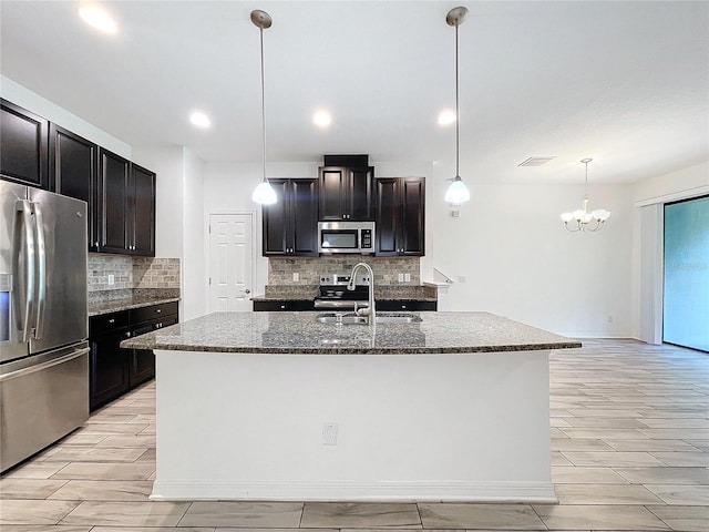 kitchen with stainless steel appliances, sink, and a kitchen island with sink