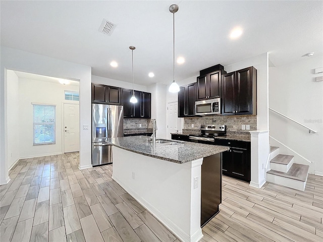 kitchen featuring light hardwood / wood-style flooring, appliances with stainless steel finishes, sink, and a kitchen island with sink