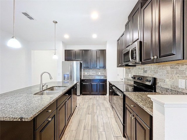 kitchen featuring dark brown cabinets, backsplash, sink, pendant lighting, and stainless steel appliances