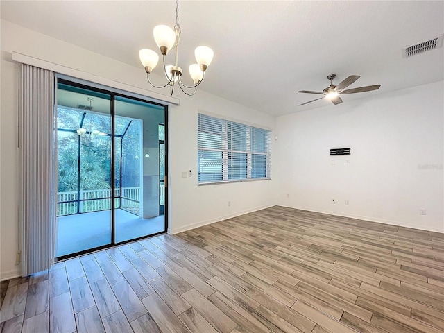 spare room featuring wood-type flooring and ceiling fan with notable chandelier