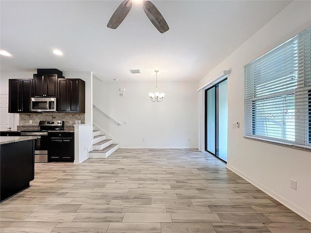 kitchen featuring tasteful backsplash, light stone countertops, ceiling fan with notable chandelier, stainless steel appliances, and decorative light fixtures