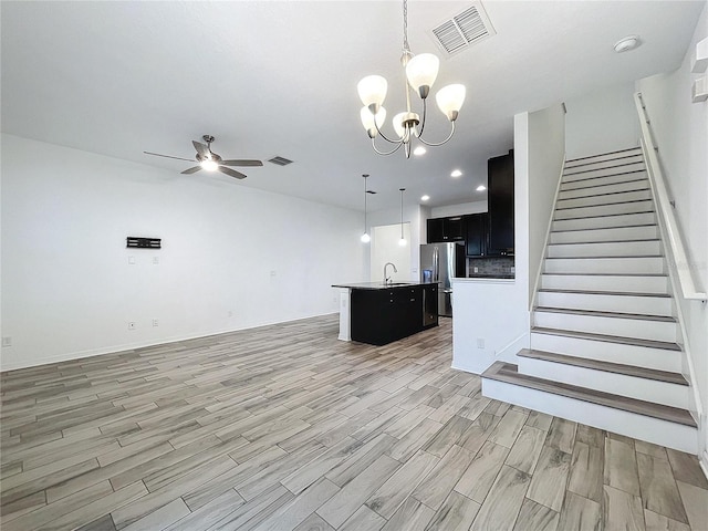 unfurnished living room with sink, light hardwood / wood-style flooring, and ceiling fan with notable chandelier